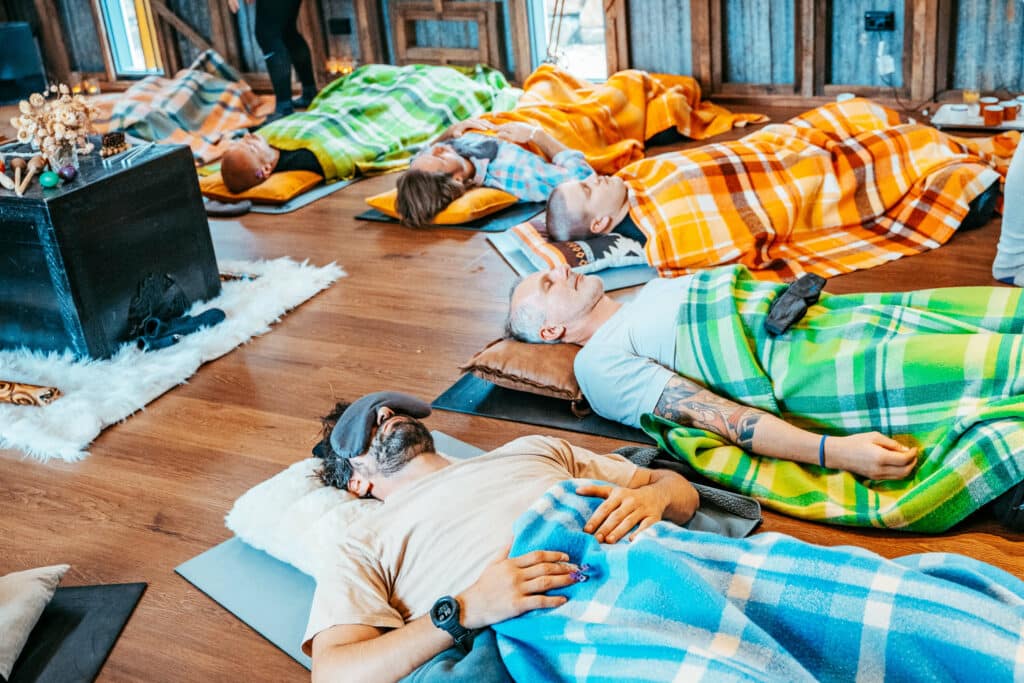 A group of people lying on pillows and practicing breathwork for the first time.
