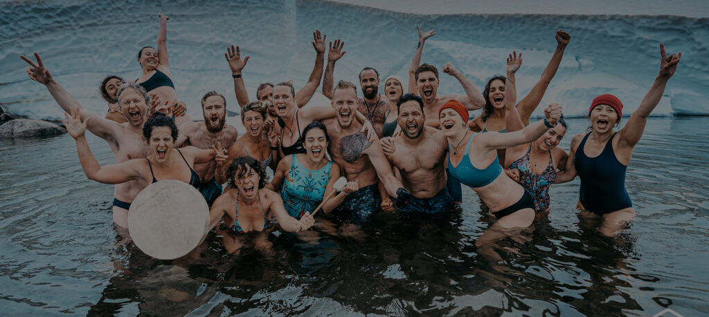 A group of people who are breathwork instructor students in a river cheering.