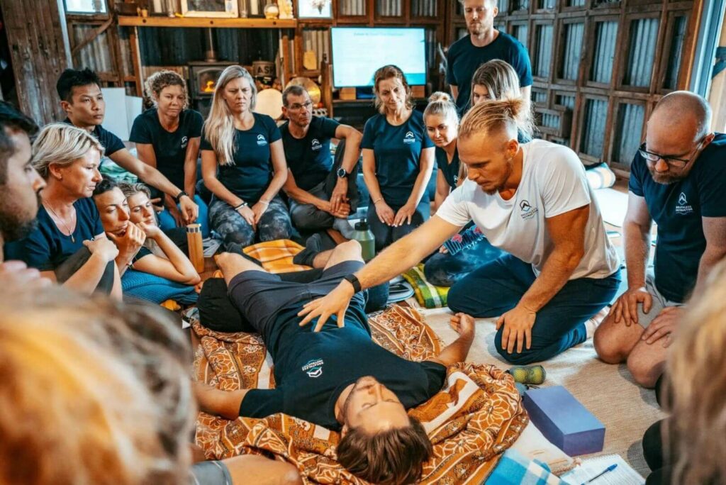 A breathwork facilitaor teaching a group of people how to train others in breathwork.