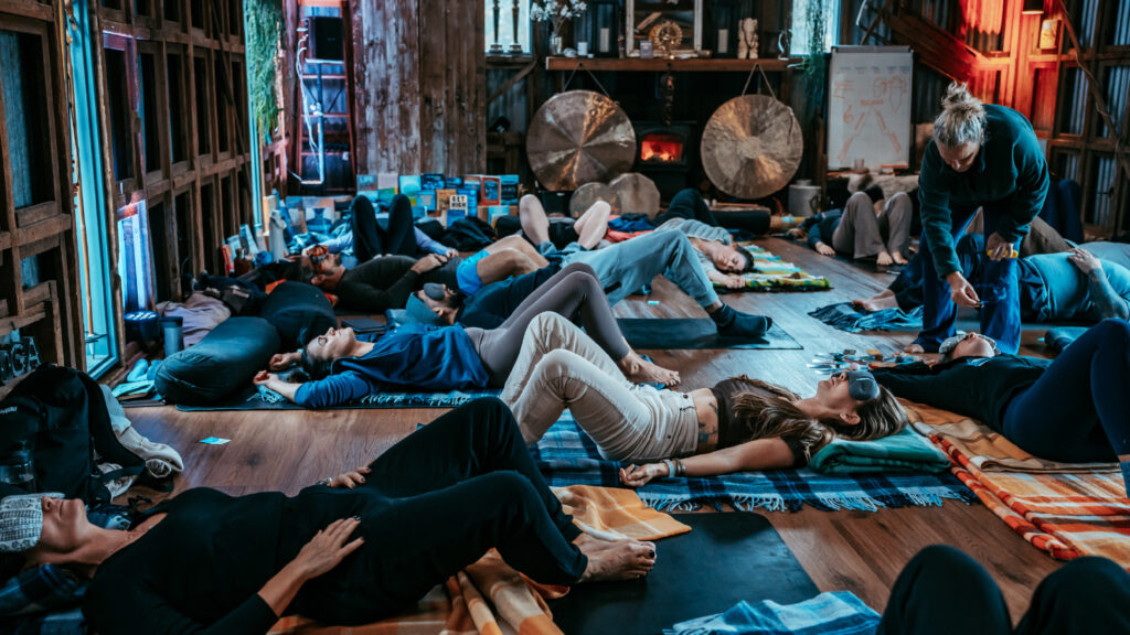 A group of people during a breathwork practice lying on mats in a room