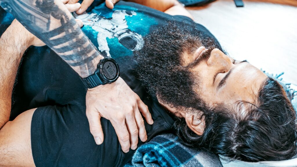 A man lying on a couch pratising slow breathing with someone's hand on his chest.