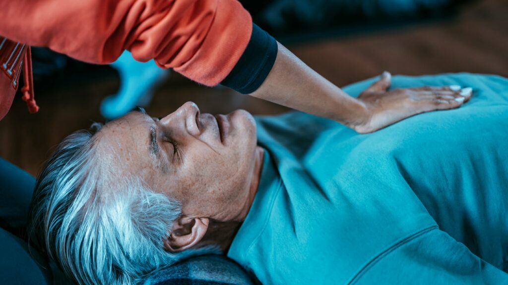 A person layin gon the floor practising breathing exercises to lower blood pressure.