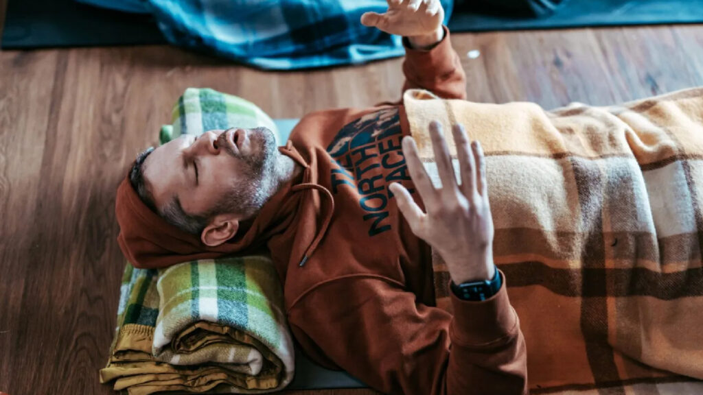 A man with his hands in the air during breathwork practice.